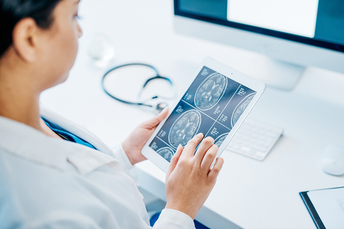 A researcher looks at brain imaging on a tablet in a lab.